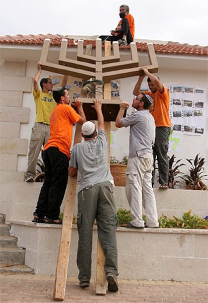 Colonos de Netzarim retiran el candelabro judío del tejado de la sinagoga del asentamiento.