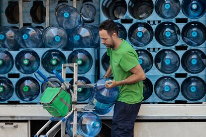 Un trabajador transporta bidones de agua.