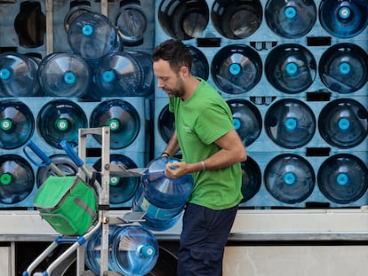 Un trabajador transporta bidones de agua.