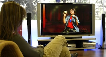 Una mujer, frente a un televisor de pantalla plana. 