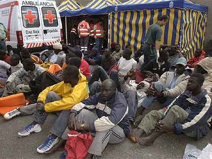 Inmigrantes llegados ayer al muelle de Arguineguín, en Canarias, son atendidos por la Guardia Civil y la Cruz Roja.