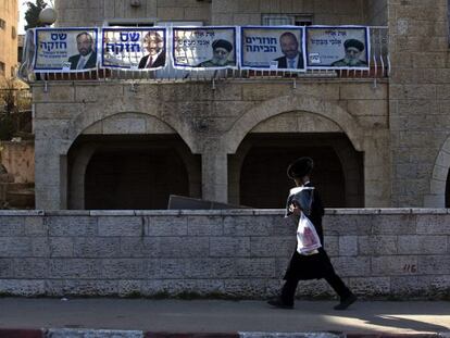 Un joven ultraortodoxo pasa ante una casa decorada con carteles del partido religioso sefard&iacute; Shas, en Jerusal&eacute;n. 