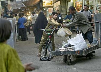 Un niño iraquí compra pan a un vendedor ambulante en una calle de Bagdad.