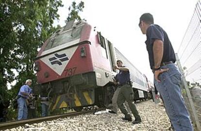 La policía israelí y trabajadores del tren inspeccionan los daños causados por el atentado.