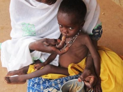 Una mujer alimenta a su hijo con pasta de cacahuete.