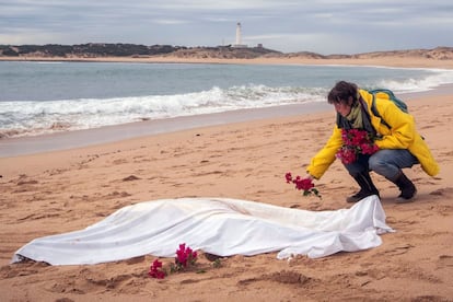 Una mujer coloca unas flores alrededor de uno de los cadáveres aparecidos de los inmigrantes que naufragaron en una patera el pasado lunes en la costa de Caños de Meca (Cádiz).