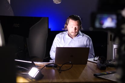 Ken Joyce - Looking down at laptop, blue shirt, sitting, shadow on right of his face