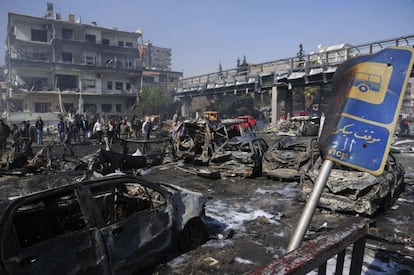 Un grupo de personas observan el lugar del atentado tras explotar un coche bomba en el centro de Damasco, Siria.