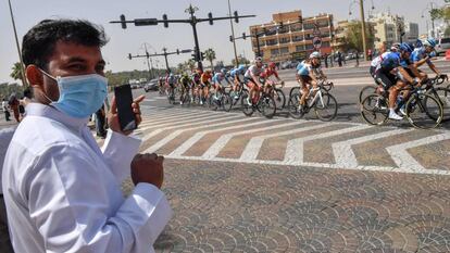 Un aficionado con mascarilla observa el paso del pelotón durante el UAE Tour antes de que la carrera se suspendiese por el coronavirus.