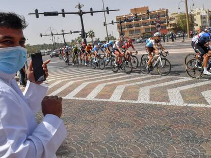 Un aficionado con mascarilla observa el paso del pelot&oacute;n durante el UAE Tour antes de que la carrera se suspendiese por el coronavirus.