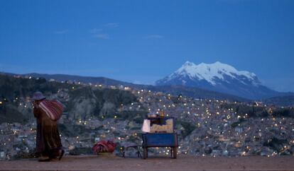 Una mujer camina por la Avenida Periférica, pasando por un puesto callejero de palomitas de maíz, conocido como "pipocas", en La Paz (Bolivia).