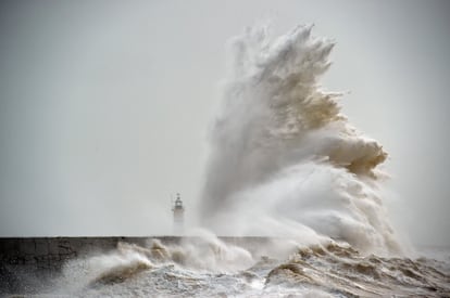Una ola golpea el faro Newhaven, al sur de Inglaterra.