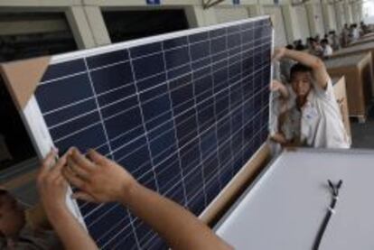 HHY05 BAODING (CHINA), 04/06/2013.- Fotografía de archivo fechada el 2 de agosto de 2012 que muestra a unos empleados sosteniendo un panel solar en la factoría de Yingli Green Energy Holdings en Baoding, en China. La Comisión Europea (CE) impuso hoy un arancel temporal del 11,8 % a las importaciones de paneles solares desde China, una tasa que aumentará al 47,6 % a partir del próximo 6 de agosto si Pekín no encuentra antes una solución negociada. EFE/How Hwee Young
