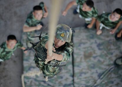 Un miembro de la policía paramilitar china trepa por una cuerda durante un entrenamiento en Chongqing (China).