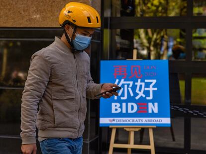 Un repartidor pasa delante de un bar en Shanghái donde se ha seguido el recuento de las elecciones de EE UU.