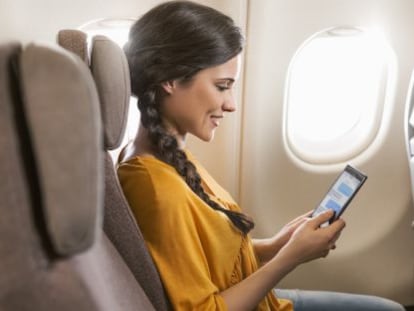 Una pasajera consulta su tableta en un vuelo intercontinental de Iberia.