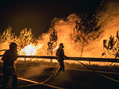 Operarios de las Brigadas de Refuerzo de Incendios Forestales (BRIF) luchan contra las llamas en la madrugada de este sábado para extinguir el incendio declarado en el día anterior en la parroquia de Boiro.