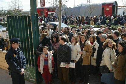 Una gran fila de personas aguarda para votar en el colegio electoral Madrid Sur, frente a la estación de cercanías de El Pozo, durante la jornada de votaciones del 14-M. Al fondo, uno de los trenes en los que perecieron decenas de personas, víctimas de los atentados contra varios trenes de cercanías en Madrid.