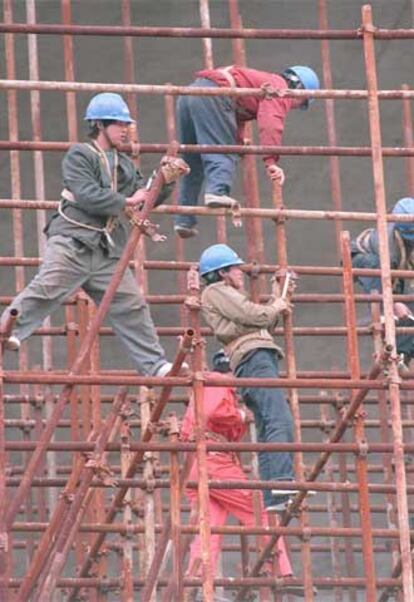 Trabajadores chinos montan una estructura metálica.