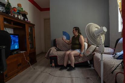 Una mujer con el ventilador encendido ve la televisión en su departamento en Ciudad de México.