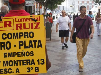 Un hombre porta un anuncio de una empresa de compra de oro en Madrid
