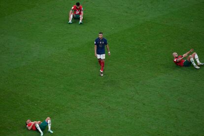  Kylian Mbappé, en el centro, camina entre tres jugadores tumbados en el césped tras caer eliminados en las semifinales del Mundial de Qatar ante Francia. 