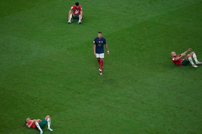 Kylian Mbappé, en el centro, camina entre tres jugadores tumbados en el césped tras caer eliminados en las semifinales del Mundial de Qatar ante Francia.