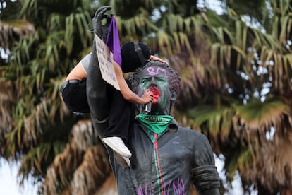 Una mujer pinta la estatua de Luis Carlos Galán, durante la marcha del 8M, en Bogotá