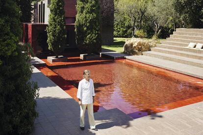 Ricardo Bofill junto a la piscina roja. Tras los cipreses la estructura cúbica acristalada, también roja, hace las veces de comedor.