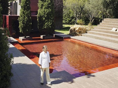 Ricardo Bofill junto a la piscina roja. Tras los cipreses la estructura cúbica acristalada, también roja, hace las veces de comedor.