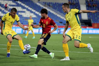El delantero de la selección española sub21, Javi Puado, controla el balón ante dos jugadores de Lituania.