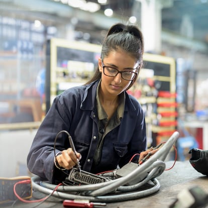 Female apprentice electrician in car factory