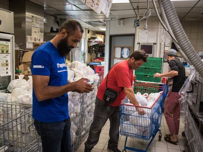 Kamel Guemari (izquierda), antiguo empleado de McDonald's, prepara bolsas de comida para su distribución junto a dos voluntarios.