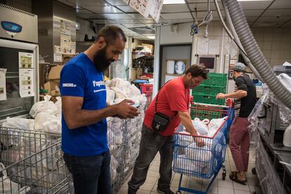 Kamel Guemari (izquierda), antiguo empleado de McDonald's, prepara bolsas de comida para su distribución junto a dos voluntarios.