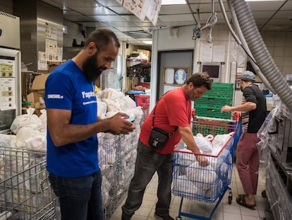 Kamel Guemari (izquierda), antiguo empleado de McDonald's, prepara bolsas de comida para su distribución junto a dos voluntarios.