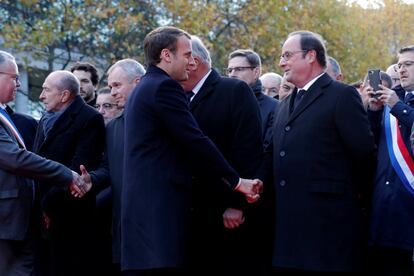 El presidente Emmanuel Macron (izq) le da la mano al expresidente, Françoise Hollande, frente a la placa conmemorativa en la entrada al Estadio de Francia en Saint-Denis, cerca de París.
