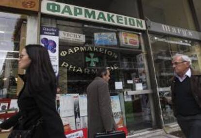 Varios peatones caminan junto a una farmacia cerrada debido a la huelga de un día convocada en Atenas, Grecia, el 11 de diciembre del 2012, para protestar por los impagos del Gobierno del país.