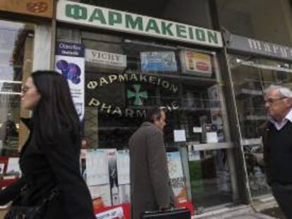 Varios peatones caminan junto a una farmacia cerrada debido a la huelga de un día convocada en Atenas, Grecia, el 11 de diciembre del 2012, para protestar por los impagos del Gobierno del país.