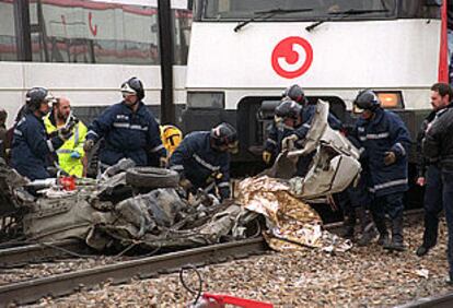 Los bomberos trabajan entre los restos del coche arrollado por un tren en Villaverde Alto.