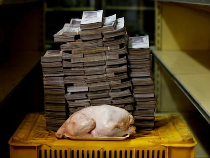 Un pollo de 2,4 kilos frente a una montaña de billetes que suman su precio —un equivalente de 1,95 euros—, en un mercado de Caracas, el 16 de agosto de 2018.