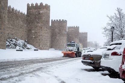 Una máquina quitanieves trabaja para retirar la nieve caída junto a la muralla de Ávila.