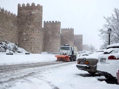 Una máquina quitanieves trabaja para retirar la nieve caída junto a la muralla de Ávila.