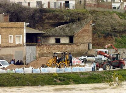 Una excavadora construye un dique para proteger unas casas de la crecida del Ebro a su paso por la localidad zaragozana de Gallur.