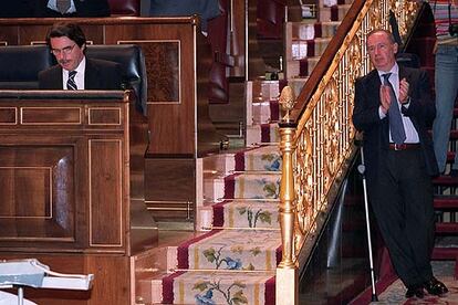 En la foto, el presidente del Gobierno José María Aznar permanece en su escaño, mientras el vicepresidente segundo, Rodrigo Rato aplaude, ayudado por una muleta tras una operación en un pie.