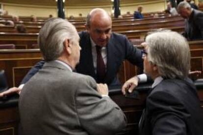 El ministro de Economía y Competitividad, Luis de Guindos (c), conversa con el diputado de CiU, Josep Sánchez Llibre (d), durante su intervención en la sesión de control al Gobierno que se celebra hoy en el Congreso de los Diputados.