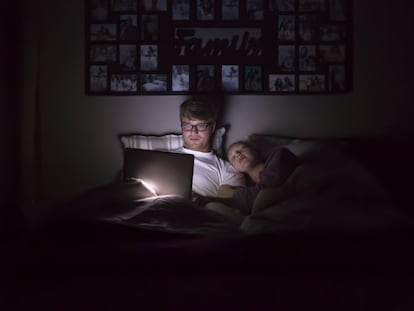 Un hombre utiliza un ordenador portátil desde la cama durante la noche.