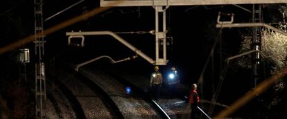 Security personnel inspect the railway after a train crash near Manresa