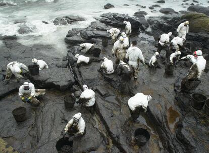 Voluntarios limpian hoy el fuel en las rocas de la playa de Coído, en Muxía, afectada por el vertido del petrolero Prestige.