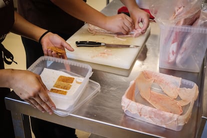 Dos trabajadores de cocina preparan la piel de pollo para freírla y transformarla en la cubierta de un sándwich.