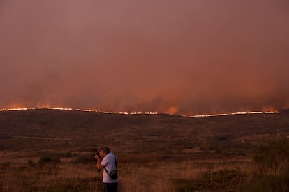 Un hombre toma una fotografía en medio del incedio en Randin, Ourense.